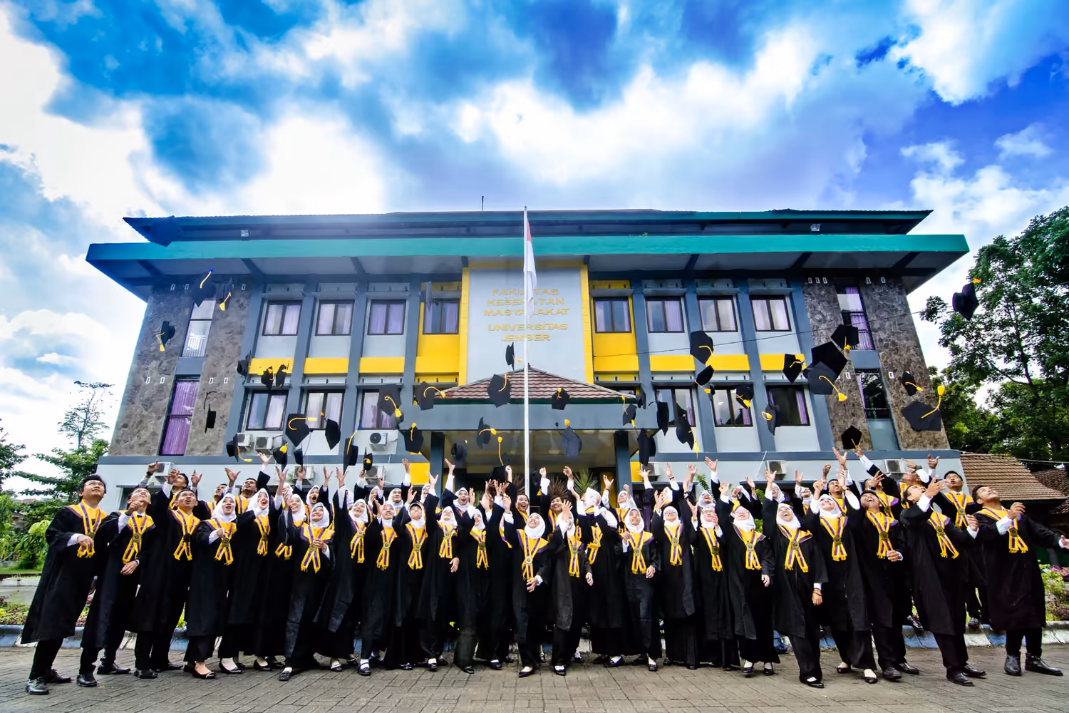 Mahasiswa Fakultas Kesehatan Masyarakat Universitas Jember melempar topi wisuda di depan Gedung Dekanat